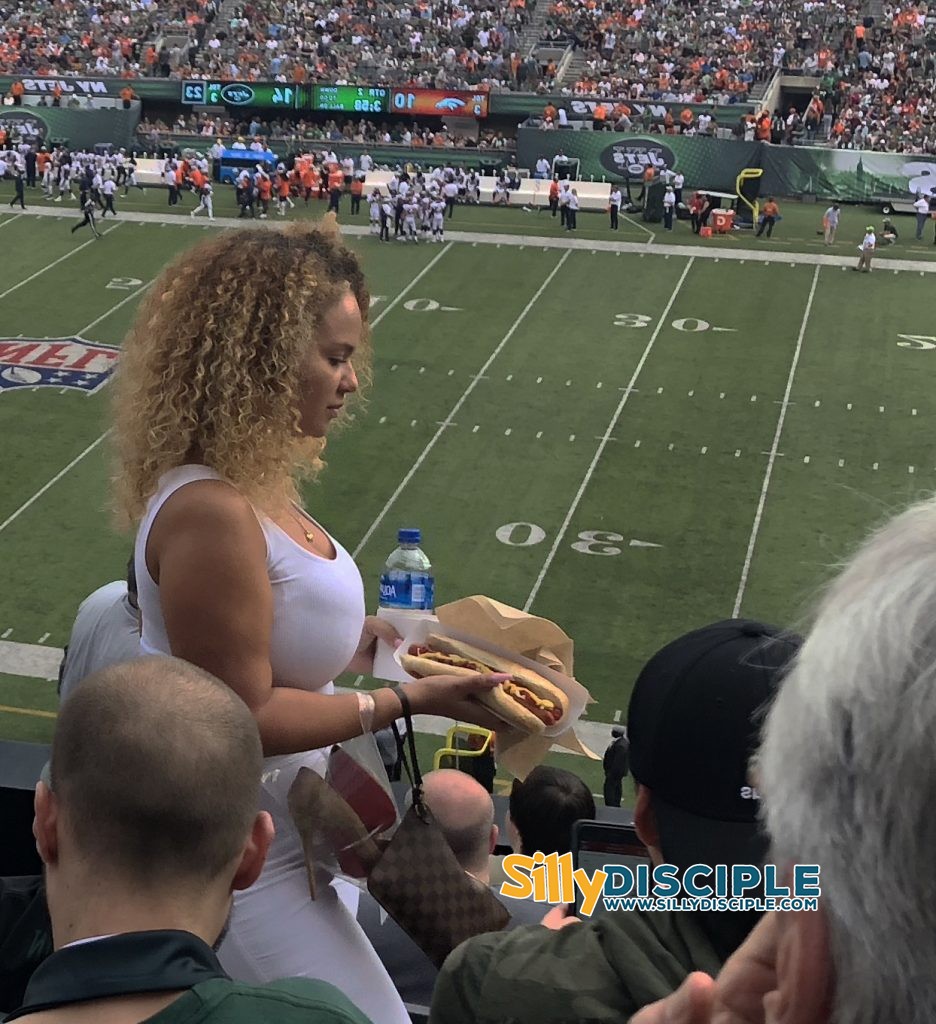 Busty girl carries a hot dog on football stadium